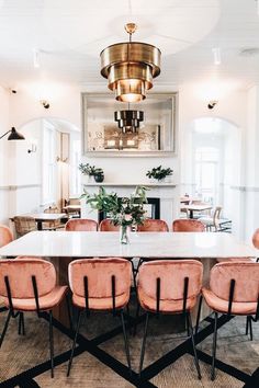 a dining room table with pink chairs and a fireplace