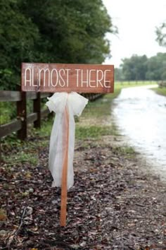 a sign that says almost there hanging on the side of a road with trees in the background