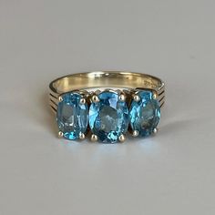 14K Yellow Gold Three Stone Blue Topaz Ring, Size 6.5, 3.6 grams, December Birthstone Size: 6.5 Weight: 3.6grams Stones: Blue Topaz Size Main Stone: ca. xxmm x xxmm, Oval Cut (1 stone) Size Secondary Stone: ca. xxmm x xx1mm, Oval Cut (2 stones) Color Gemstone: Blue Number of Gemstones: 3 Markings: 14K 585 Metal Purity: Solid 14 Karat Gold Bandwidth: ca. 2.5mm at smallest point  Tested: Presidium Gem Tester PGT/CSE/PGT2 (testing performed by 3rd person) Condition: Good preowned with light usage throughout -refer to pictures for condition. All jewelry will be professionally cleaned before shipping and come in a beautiful little gift box. Returns accepted but are subjected to a 8% restock fee. Returns are only accepted for national orders and all orders will be shipped with tracking. Blue Topaz Three Stone Blue Jewelry, Formal Blue Topaz Three Stone Ring, Fine Jewelry Blue Topaz Three Stone Ring, Formal Blue Birthstone Ring With Three Stones, Heirloom Blue Three-stone Ring, Three-stone Blue Topaz Ring For Anniversary, Blue Topaz Three Stone Ring For Anniversary, Anniversary Three-stone Blue Topaz Ring, Blue Topaz Three-stone Ring