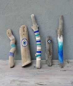 five wooden sculptures are lined up against a wall, one is painted blue and the other has an eye on it