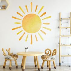 two chairs and a table in front of a wall with the sun painted on it