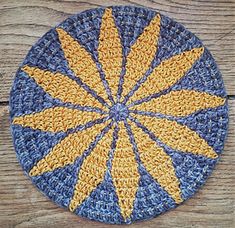 a crocheted blue and yellow plate on wooden table