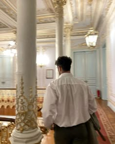 a man is standing in the middle of a room with columns and gold trimmings