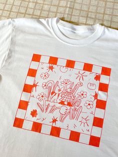 an orange and white t - shirt with flowers on it