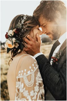 a man and woman standing next to each other in front of the sun with flowers on their head