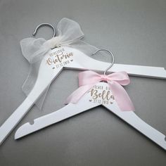 three white hangers with pink bows and personalized names on them, one is for a baby