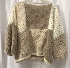 a crocheted sweater hanging on a hanger