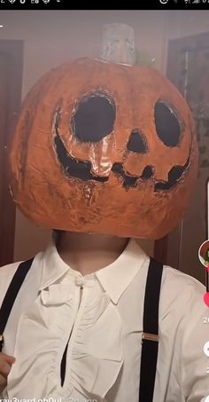 a person wearing a fake pumpkin mask on their head