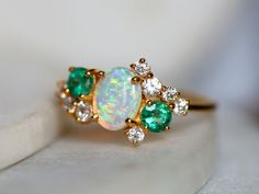 an opal and diamond ring on a white surface