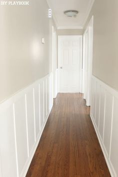 an empty hallway with hard wood floors and white walls