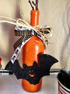 an orange bottle with a bat decoration on the top and ribbon tied around it's neck