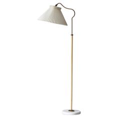 a white floor lamp with a wooden base and a beige shade on the top of it