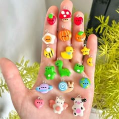 a hand holding many different shaped charms on it's palm with plants in the background