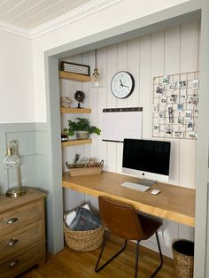 a desk with a computer on it in front of a wall mounted clock and other items