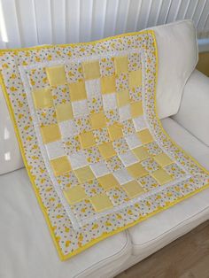 a yellow and white quilt sitting on top of a couch