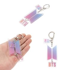 a hand holding two different key chains and one with the letter btts on it