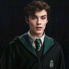 a young man wearing a green and black harry potter robe