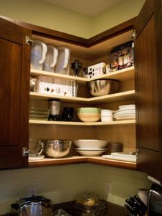 an open cabinet with bowls and pans in it