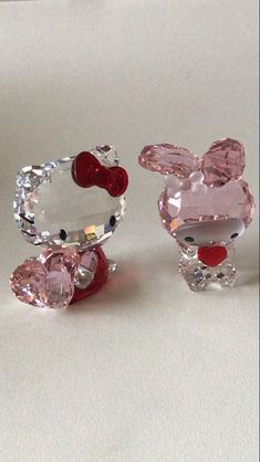 three different types of glass animals on a white surface with red and pink stones in the middle