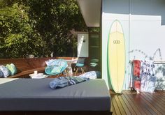 a bed sitting on top of a wooden floor next to a surfboard