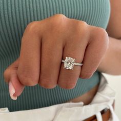 a woman's hand with a diamond ring on her finger, showing the middle finger