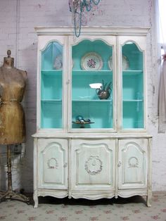 a white china cabinet with glass doors and drawers in front of a mannequin's dummy