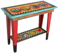 a wooden table with colorful designs on the top and bottom shelf in front of it