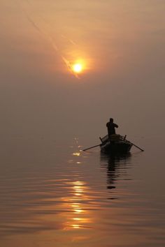 a person in a boat on the water at sunset