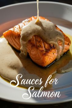 salmon being drizzled with gravy on top of a white plate