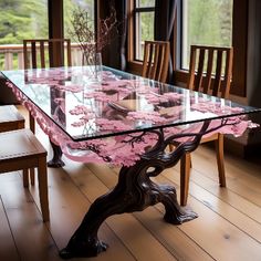 a glass table with pink flowers on it in front of large windows and wooden chairs