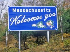 a blue sign that says massachusetts gets welcomes you with flowers and birds on it