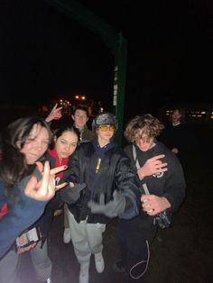 a group of people standing next to each other on top of a field at night