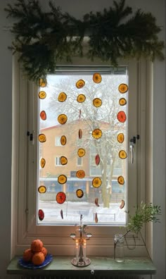 the window is decorated with oranges and pine cones