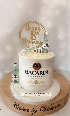 a birthday cake that is sitting on top of a wooden stand with alcohol bottles in front of it