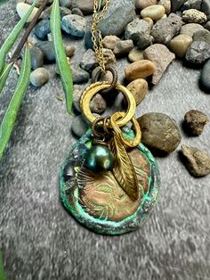 a necklace with a bird on it sitting on some rocks