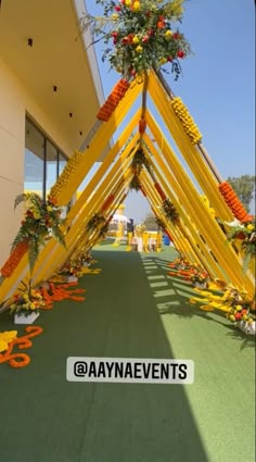 the entrance to an event decorated with flowers and orange ribbon tied around it's poles