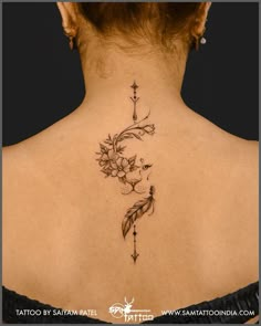 the back of a woman's neck with flowers and an arrow tattoo on it