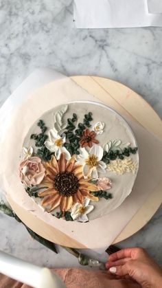 someone is decorating a cake with flowers on it