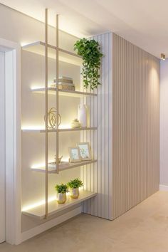 a white shelf with plants and pictures on it in a room that is lit up