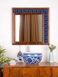 a blue and white bowl sitting on top of a wooden table next to a mirror