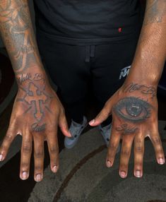 two hands with different tattoos on them and one has an eye in the middle, while the other holds out his hand