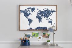 the world map is made out of blue beads on a white wall above a desk