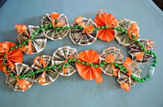 dollar bills and orange bows are arranged in the shape of an origami wreath