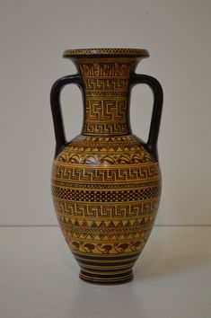 a large vase with designs on it sitting on a white counter top next to a wall