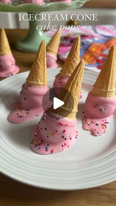 ice cream cones with pink icing and sprinkles on a white plate