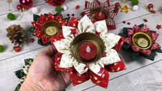 a person is holding a red and white flower with two candles on top of it