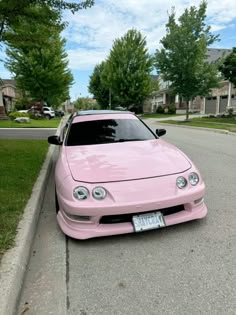 the pink car is parked on the side of the road