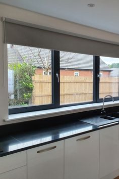 a kitchen with black counter tops and white cupboards next to a sliding glass door