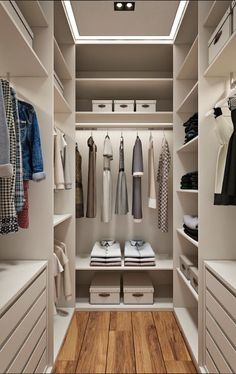 an organized walk - in closet with white drawers and clothes hanging on the shelves,