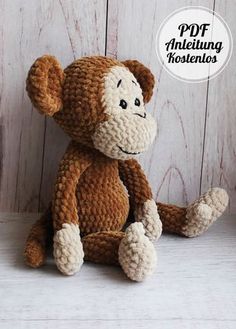 a crocheted monkey sitting on top of a white table next to a wooden wall